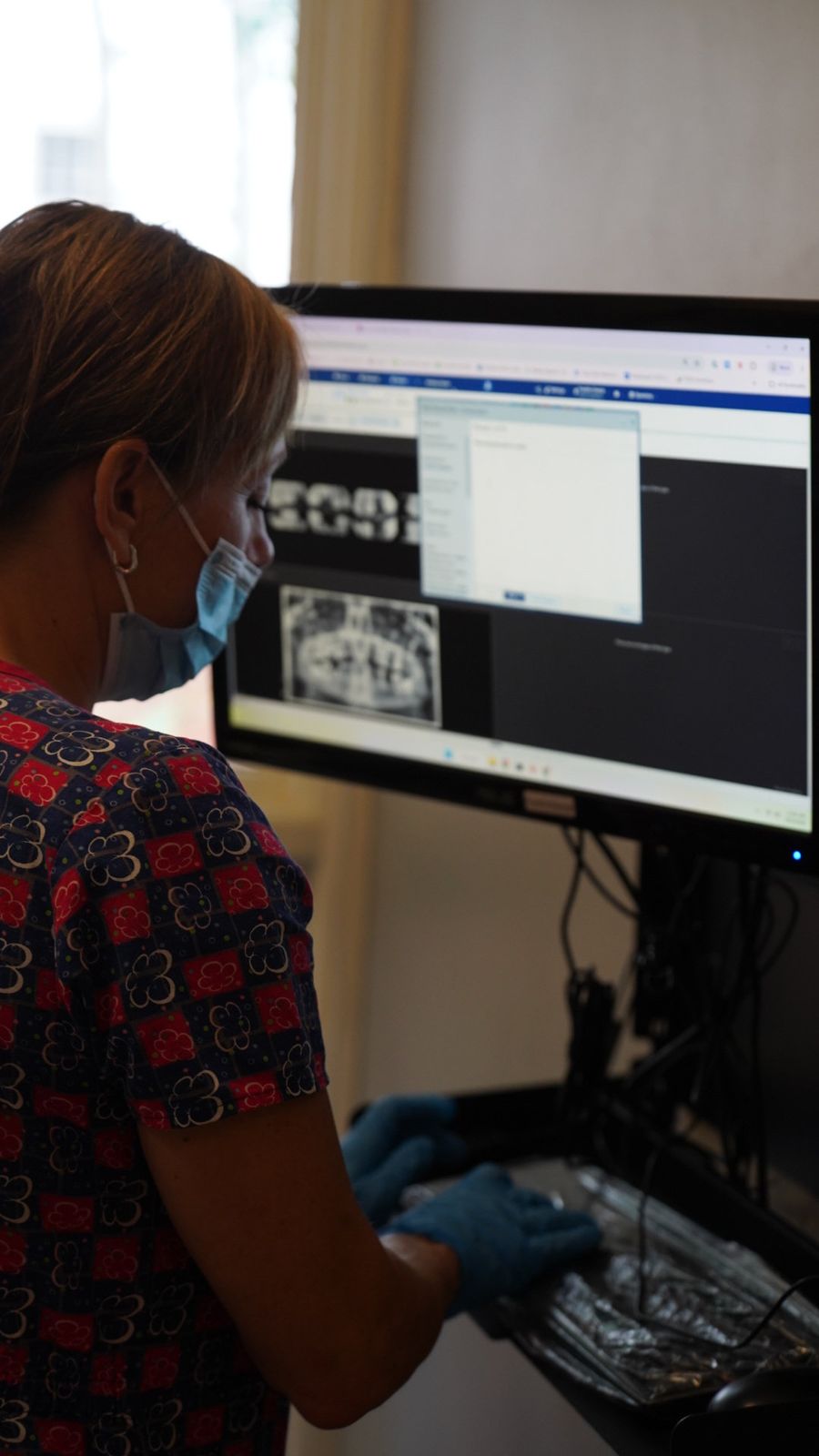 A staff member reviewing dental x-rays on a monitor
