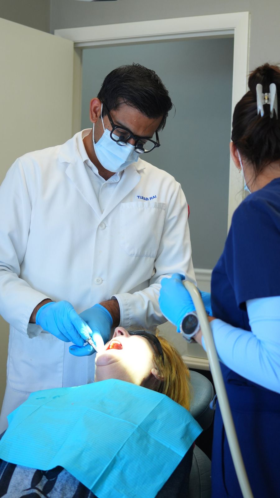 Dr. Rai treating a patient with an assistant beside him